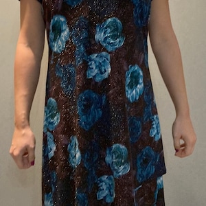 May include: A short-sleeved dress with a dark brown background and a blue floral pattern. The dress has a scoop neck and a slightly flared skirt.