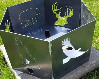Könnte beinhalten: Ein sechseckiger Feuerplatz aus Metall mit Ausschnitten eines Bären, eines Hirsches, eines Wolfes und eines Adlers. Der Feuerplatz steht auf einem Betonblock.