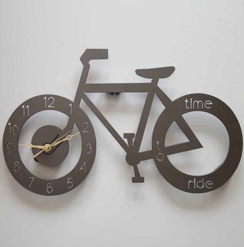 May include: A brown metal wall clock shaped like a bicycle with the words "time to ride" on the back wheel.