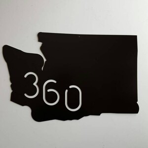 Op de afbeelding: Zwarte metalen omtrek van de staat Washington met het nummer 360 uitgesneden in wit.