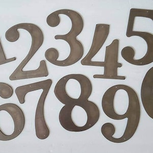 May include: Ten metal numbers, 1 through 10, in a rustic brown finish. The numbers are cut out of metal and have a slightly distressed look.