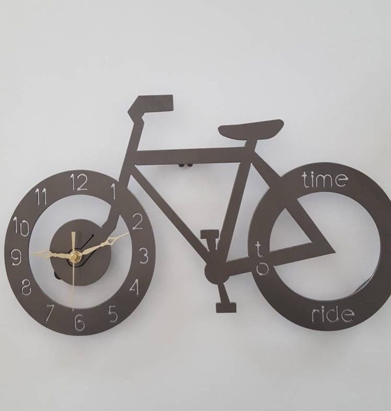 May include: A black metal wall clock shaped like a bicycle with the words "time to ride" on the wheels. The clock face is on the front wheel.