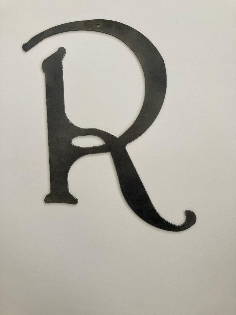 May include: A metal letter R with a decorative, cursive font. The letter is black and has a hole at the top for hanging.