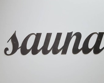 Könnte beinhalten: Ein schwarzes Metallschild mit dem Wort "Sauna" in kursivschrift.