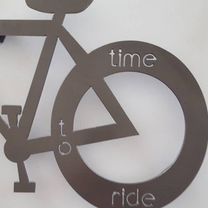 May include: A metal silhouette of a bicycle with the words "time to ride" inscribed on the front wheel.