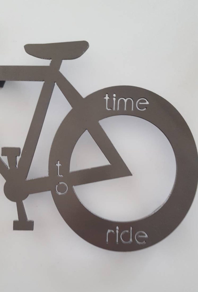 May include: A metal silhouette of a bicycle with the words "time to ride" inscribed on the front wheel.