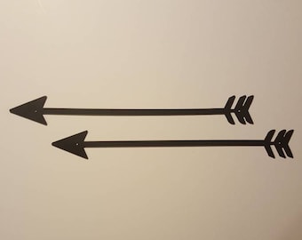 May include: Two black metal arrows pointing to the left, mounted on a white wall.