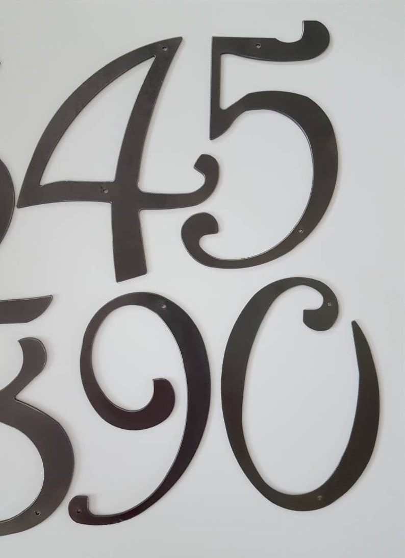 May include: A set of black metal house numbers in a decorative script font. The numbers are 4, 5, 3, 9, and 0.