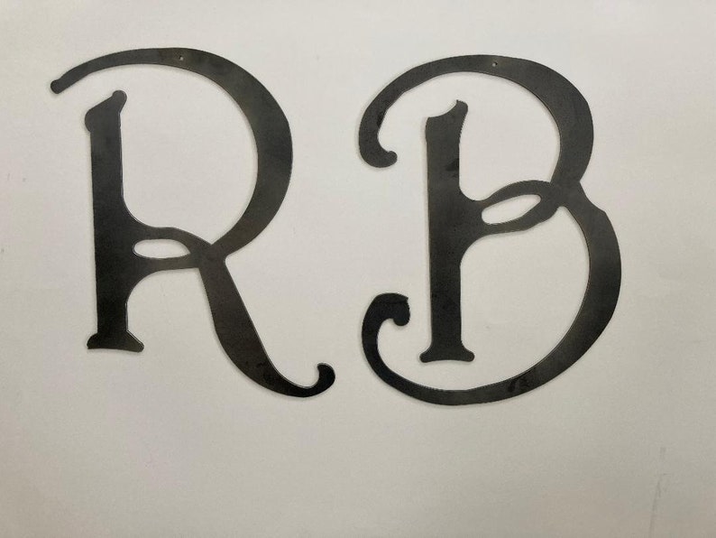 May include: Two black metal letters, R and B, in a decorative script font.