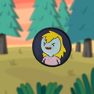 May include: A blue and yellow embroidered patch of a cartoon character with blonde hair and a pink shirt. The character has a serious expression with a raised eyebrow.
