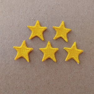 May include: Five yellow felt star-shaped patches on a brown background.