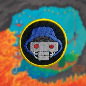 May include: A black and yellow embroidered patch with a robot wearing a blue bucket hat. The robot has red eyes and a gray face.