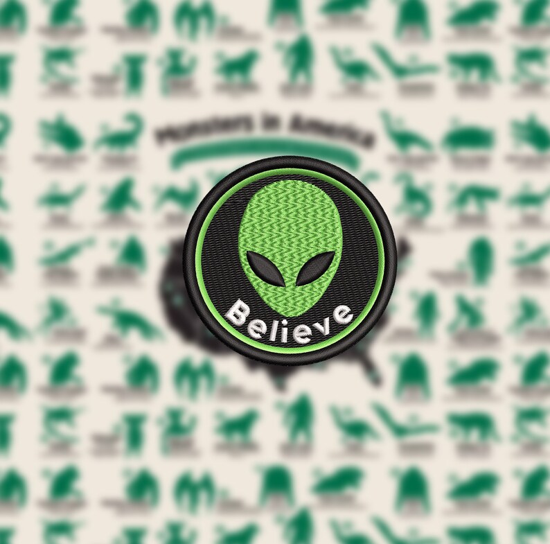 May include: Embroidered patch featuring a green alien head with black eyes on a black background, surrounded by a green border. The word "Believe" is embroidered in white. The background includes silhouettes of various monsters and the text "Monsters in America."