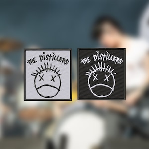 Peut inclure: Deux patchs brodés représentant le logo du groupe "The Distillers". Le logo est un visage de dessin animé stylisé avec des X pour les yeux et une moue. Un patch est blanc sur fond gris, l'autre est noir sur fond noir.