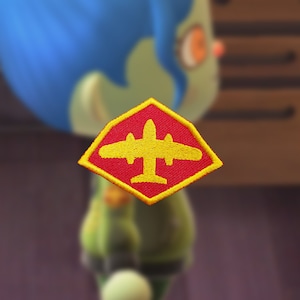 May include: A red diamond-shaped patch with a yellow airplane silhouette inside. The patch has a yellow border.