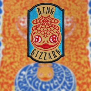 May include: A blue and yellow embroidered patch with the words "King Gizzard" and a cartoon fish with red eyes and a red mouth.
