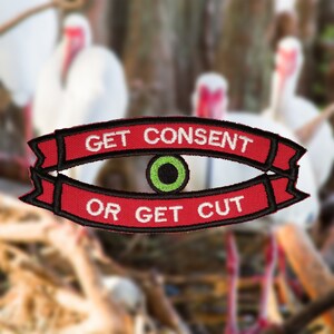 Könnte beinhalten: Roter und schwarzer gestickter Aufnäher mit einem weißen Auge und einer grünen Pupille. Der Aufnäher trägt den Text "GET CONSENT OR GET CUT" in weiß.