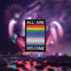 Puede incluir: Un parche rectangular con borde negro presenta el texto "ALL ARE WELCOME" arriba y abajo de un diseño de arcoíris. El arcoíris incluye los colores de la bandera del orgullo LGBTQ+ y la bandera transgénero.
