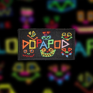 Peut inclure: Un patch brodé noir avec le mot "DOPAPOD" en lettres colorées. Les lettres sont stylisées avec différentes formes et motifs.