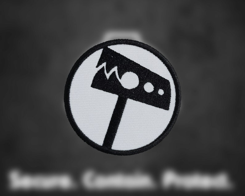 May include: A white circular patch with a black embroidered image of a hammer with a jagged edge. The hammer has a round head with two small circles.