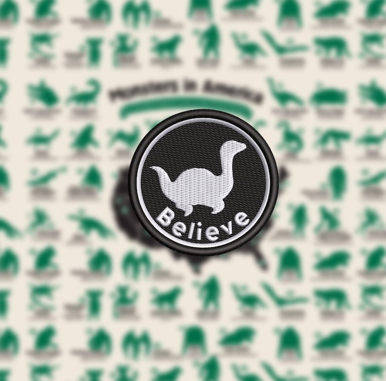 May include: Embroidered patch featuring a white dinosaur-like creature on a black background, encircled by a white border. The word "Believe" is arched below the creature. The background includes silhouettes of various creatures and the text "Monsters in America".