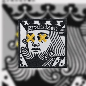 May include: Black and white embroidered patch of a king of spades playing card with the word "grandson" above the king's head. The king's eyes are covered with yellow X's.