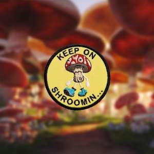 May include: A yellow embroidered patch with a red and white mushroom character wearing blue boots. The text on the patch reads "Keep on Shroomin..."