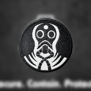 May include: Black and white embroidered patch of a stylized gas mask with a single eye hole and a rope-like design around the neck.