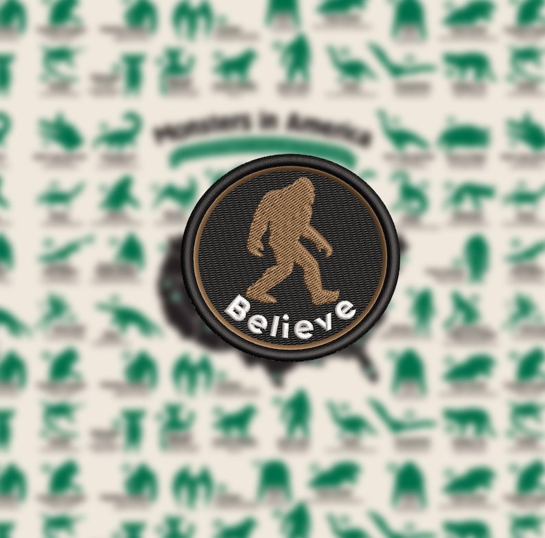 May include: A round patch featuring a brown Bigfoot silhouette walking to the left, with the word "Believe" embroidered in white. The patch has a black border with a brown inner ring. The background is a cream color with green monster illustrations.