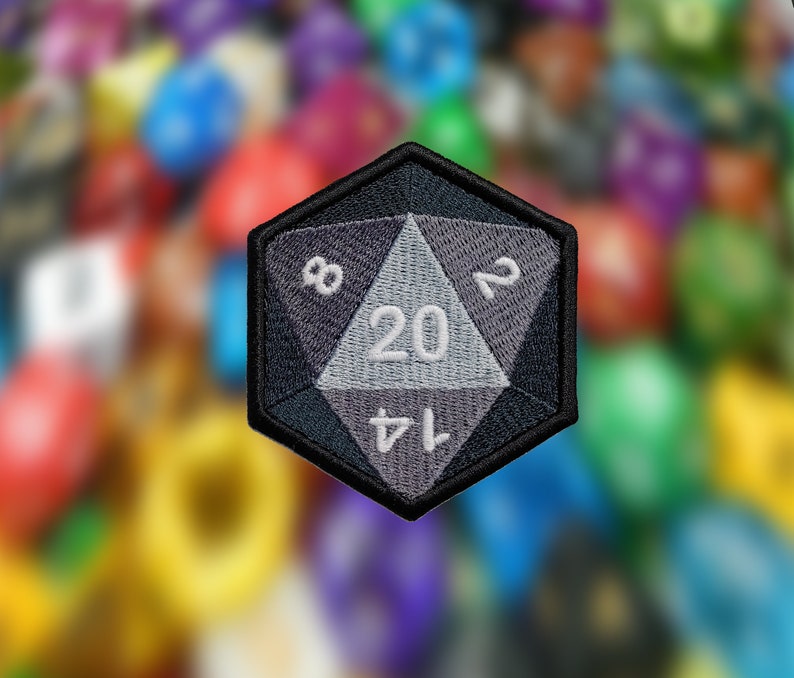 May include: A black and gray fabric patch shaped like a twenty-sided die with white numbers 8, 20, 14, and 2.