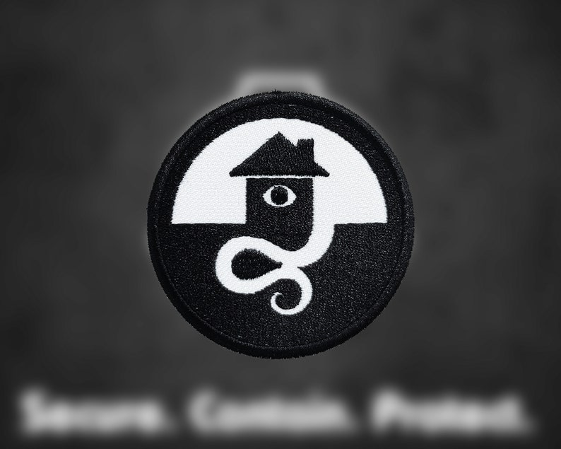 May include: Black and white embroidered patch with a house design and an eye in the window. The house is surrounded by a black and white swirl.
