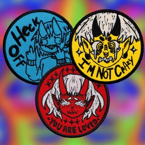 May include: Three embroidered iron-on patches featuring cartoon characters with different expressions. The first patch is blue with the text "Oh Heck" and a character with blue skin and horns. The second patch is yellow with the text "I'm Not Crazy" and a character with yellow skin and horns. The third patch is red with the text "You Are Loved" and a character with red skin and horns.