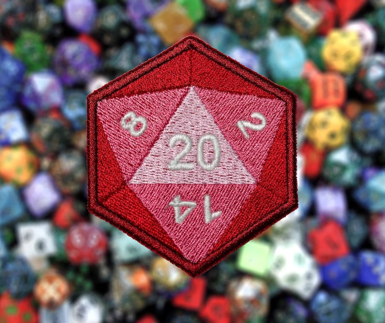May include: A red and pink embroidered patch shaped like a twenty-sided die with the numbers 1, 4, 8, 12, 16, and 20 visible.