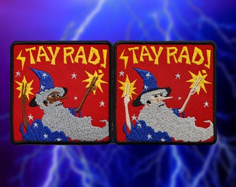 May include: Two red embroidered patches with black borders. Each patch features a cartoon wizard with a white beard and a blue hat with white stars. The wizard is holding a wand with sparks. The text "STAY RAD!" is written in yellow on each patch.