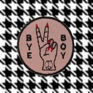 May include: Pink fabric patch with black embroidery of a hand giving the peace sign. The words "BYE BOY" are embroidered on the patch.