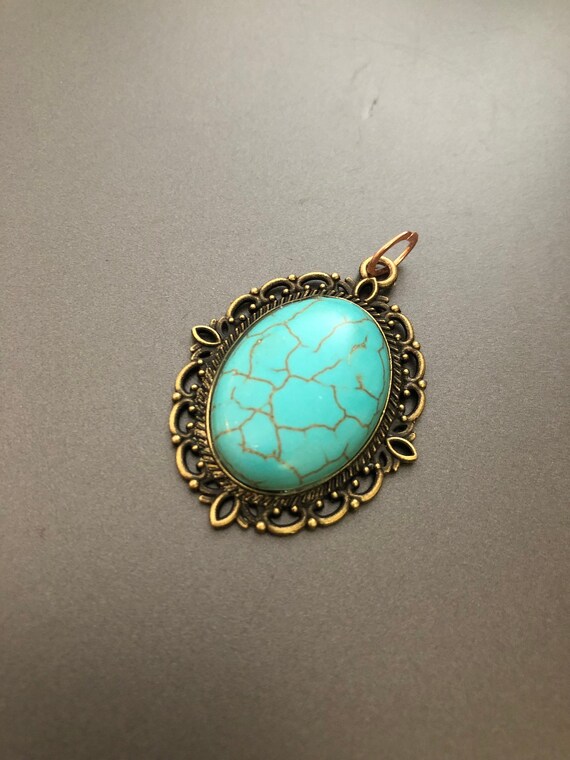 Natural Turquoise Cabochon surrounded by a Brass Setting.