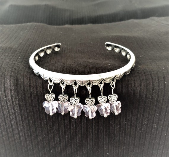 The Sparkling Pink Glass Butterflies and Silver Plated Heart Charms adorn this Bangle Bracelet