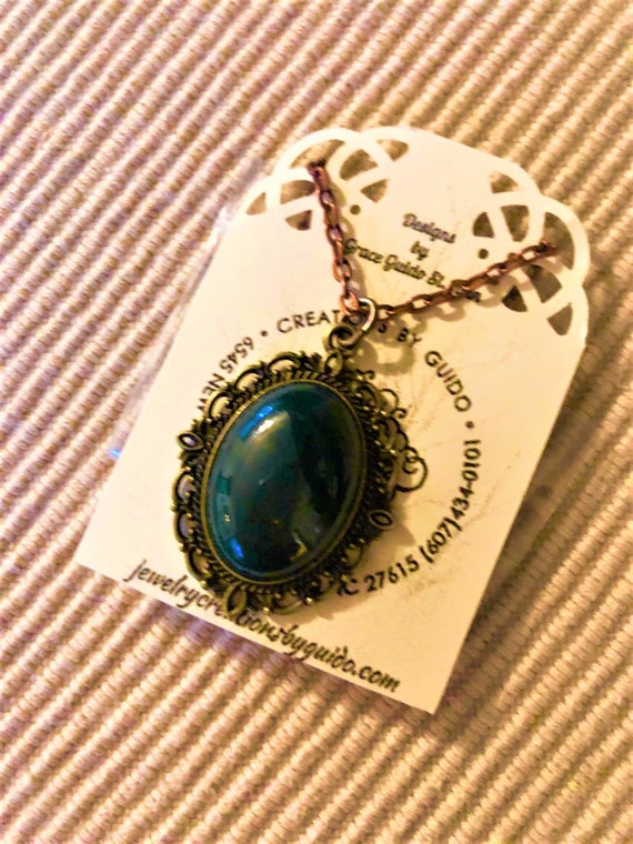 This Bloodstone pendant is accentuated by a brass setting and hangs from an antiqued copper chain.