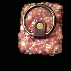 May include: A pink and white beaded keychain with a silver ring and a purple leather strap.