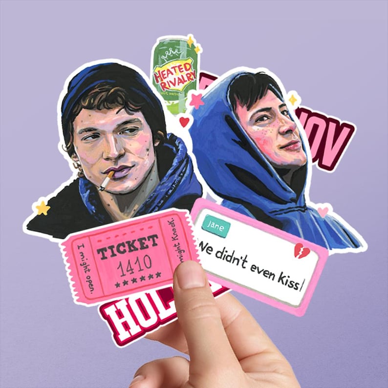 以下が含まれることがあります： パーカーを着た2人のイラスト、HEATED RIVALRYと書かれた緑色のソーダ缶、TICKET 1410と書かれたピンクのチケット、Jane We didn't even kissというテキストと壊れたハートのアイコンが描かれた白い長方形のステッカーを含むステッカーのコレクション。