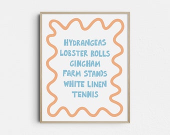 May include: A framed art print with a white background and light blue text. The text includes the words "Hydrangeas," "Lobster Rolls," "Gingham," "Farm Stands," "White Linen," and "Tennis." The text is surrounded by a wavy orange border.