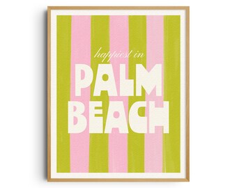 May include: A framed art print with a wooden frame. The artwork features vertical stripes in pink and green. The words "happiest in PALM BEACH" are displayed in white, bold letters.