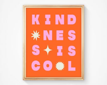 May include: A framed art print with an orange background and the words "KINDNESS IS COOL" in pink block letters. The print includes star and sunburst graphic elements, and is set in a gold frame.