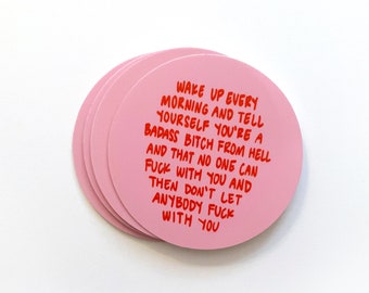 May include: A stack of pink, round stickers with red text. The text reads: "WAKE UP EVERY MORNING AND TELL YOURSELF YOU'RE A BADASS BITCH FROM HELL AND THAT NO ONE CAN FUCK WITH YOU AND THEN DON'T LET ANYBODY FUCK WITH YOU."