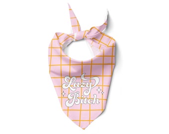May include: Pink and yellow plaid dog bandana with the text "Lazy Bitch" in a white script font. The bandana is tied at the top and features a grid pattern with yellow lines. Two small star graphics are below the text.