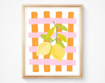 May include: A framed art print featuring a vibrant illustration of two yellow lemons with green leaves. The lemons are set against a background of orange vertical stripes and pink horizontal stripes, creating a grid pattern. The artwork is in a gold frame.
