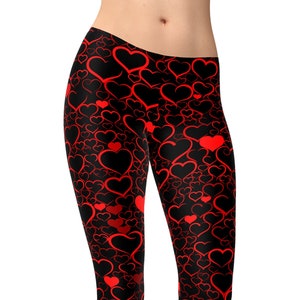 May include: Black leggings with a red heart pattern. The leggings are full length and have a tight fit.