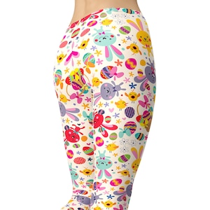 May include: White leggings with a colourful Easter-themed pattern featuring bunnies, eggs, and flowers.