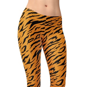 May include: Orange and black leggings with a tiger stripe pattern. The leggings are made of a stretchy, comfortable fabric and are perfect for yoga, running, or everyday wear.
