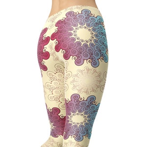 K&ouml;nnte beinhalten: Eine Leggings mit einem farbenfrohen abstrakten Muster mit Wirbeln und floralen Designs in Rosa-, Blau- und Lilat&ouml;nen auf cremefarbenem Hintergrund. Die Leggings ist von hinten zu sehen.